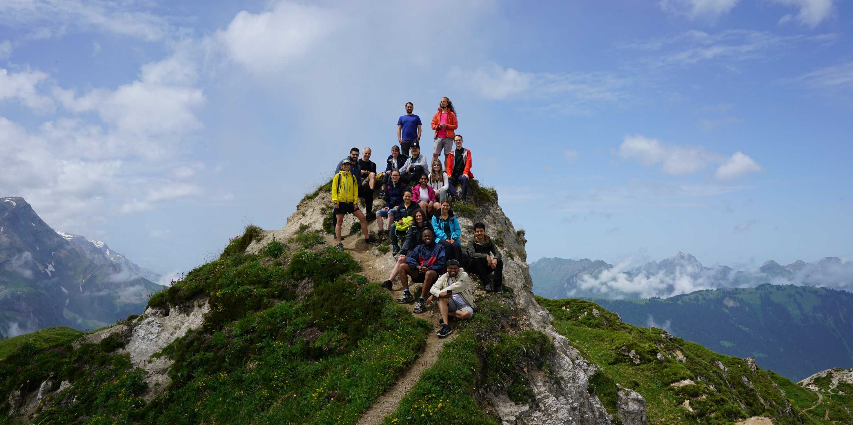 Enlarged view: Group members on top of a mountain some are standing others are sitting